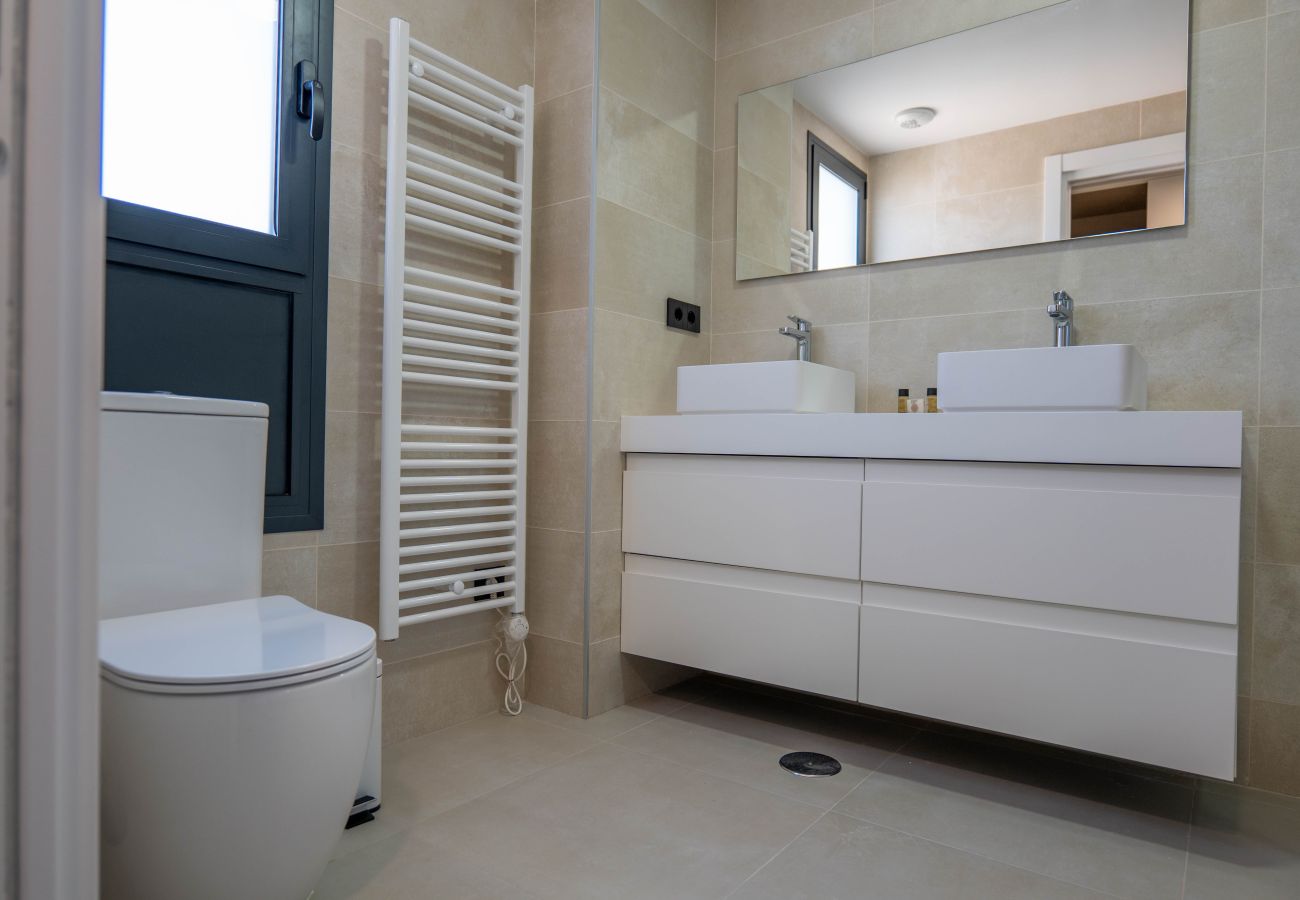 En-suite bathroom with shower, two sinks and storage space